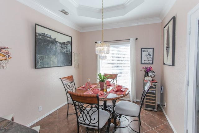 dining area featuring a tray ceiling, ornamental molding, dark tile patterned floors, and visible vents