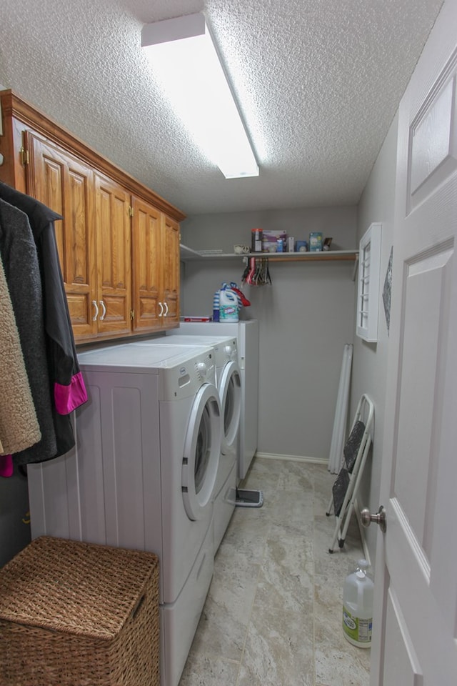 laundry area featuring washer and dryer, cabinet space, and a textured ceiling