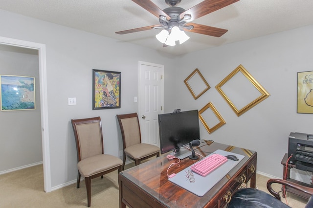 office space with a textured ceiling, baseboards, a ceiling fan, and light colored carpet