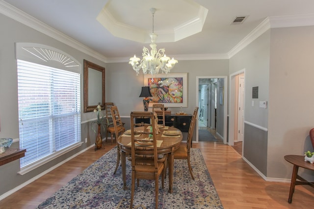 dining room featuring visible vents, a raised ceiling, wood finished floors, crown molding, and a chandelier