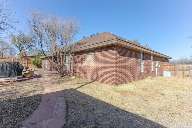 view of side of home featuring a yard, brick siding, and fence