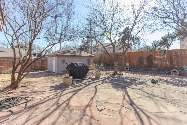 view of patio with a fenced backyard, an outdoor structure, and area for grilling