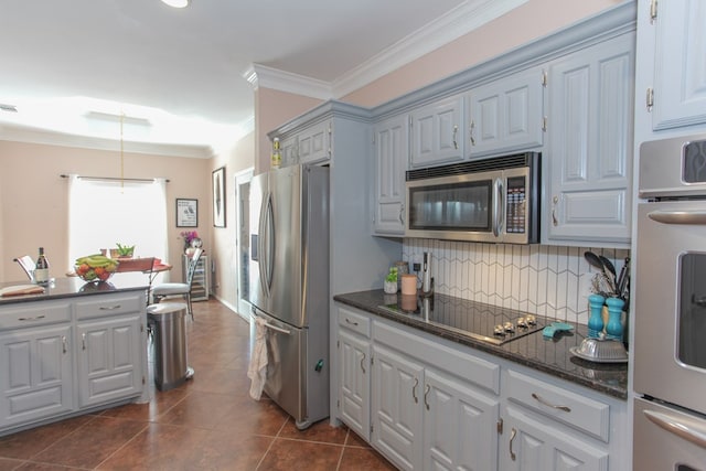 kitchen featuring stainless steel appliances, tasteful backsplash, ornamental molding, dark stone countertops, and dark tile patterned flooring