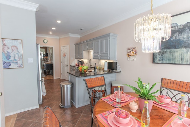 dining space with baseboards, a chandelier, dark tile patterned flooring, and ornamental molding