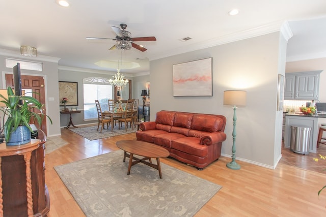 living room with light wood-style flooring, visible vents, baseboards, and ornamental molding