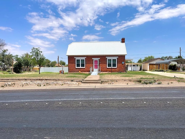 501 E 15th St, Big Spring, TX 79720 - view of front of home with a carport, brick siding, a chimney, and metal roof