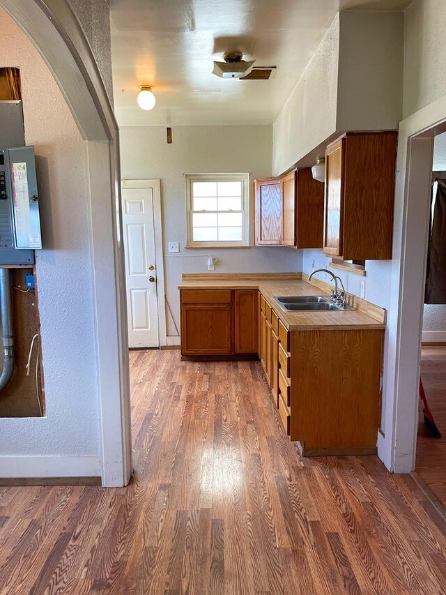 501 E 15th St, Big Spring, TX 79720 - kitchen with a sink, light wood-style floors, light countertops, arched walkways, and a textured wall