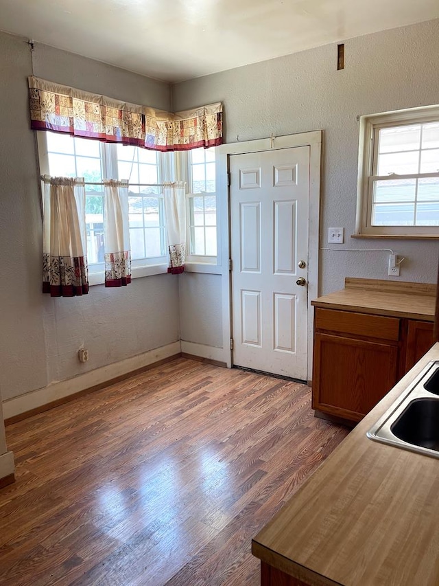501 E 15th St, Big Spring, TX 79720 - kitchen featuring wood finished floors, a sink, brown cabinetry, and baseboards