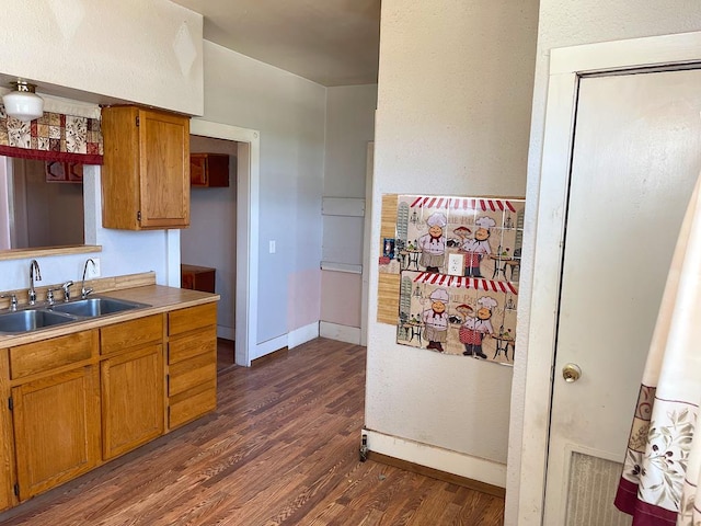 501 E 15th St, Big Spring, TX 79720 - kitchen featuring a sink, brown cabinets, dark wood finished floors, and baseboards