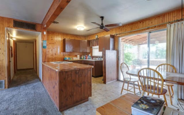1518 Stadium Ave, Big Spring, TX 79720 - kitchen with wood walls, a ceiling fan, brown cabinetry, beam ceiling, and a peninsula