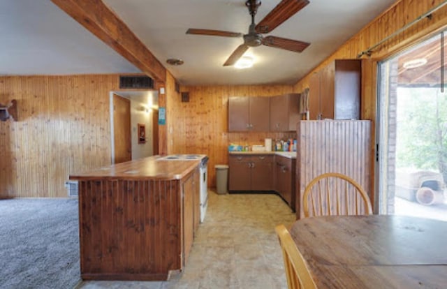 1518 Stadium Ave, Big Spring, TX 79720 - kitchen featuring wood walls, a ceiling fan, brown cabinetry, beam ceiling, and light countertops