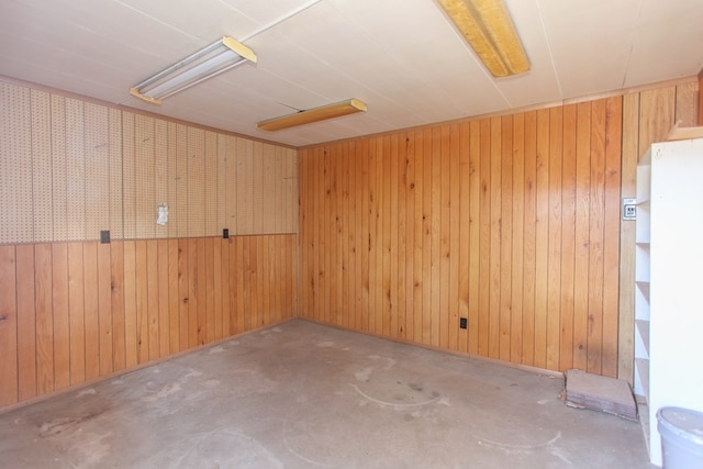 unfurnished room with wood walls and concrete flooring