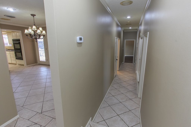 hallway with a textured ceiling, light tile patterned floors, and ornamental molding