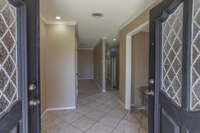 tiled foyer entrance with crown molding and a textured ceiling