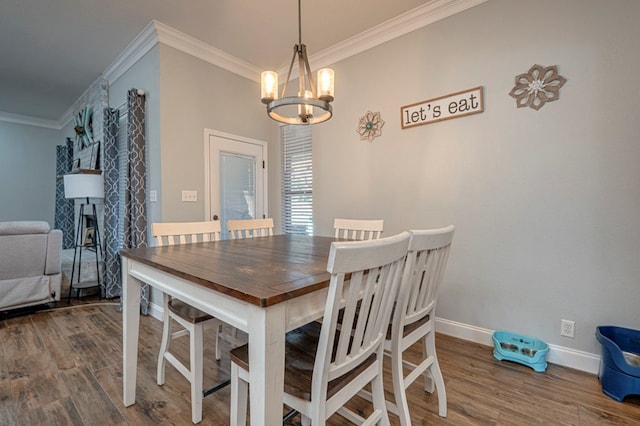 dining area featuring baseboards, ornamental molding, wood finished floors, and a notable chandelier