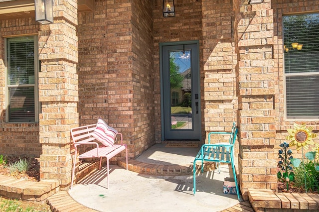 entrance to property with brick siding and a porch