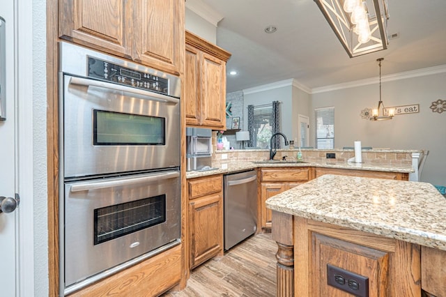 kitchen featuring crown molding, a peninsula, light wood-style floors, a sink, and stainless steel appliances