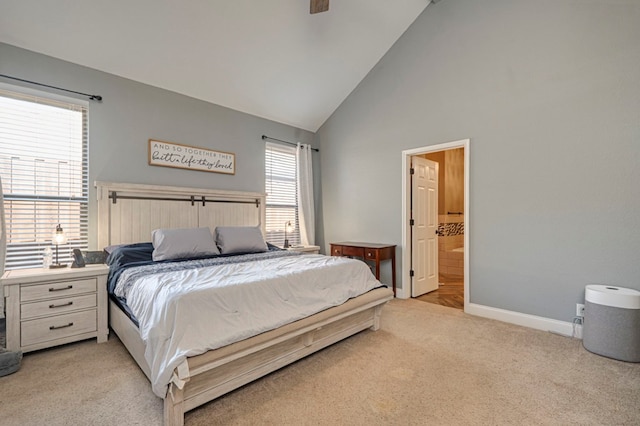 bedroom featuring ceiling fan, baseboards, high vaulted ceiling, light carpet, and ensuite bath
