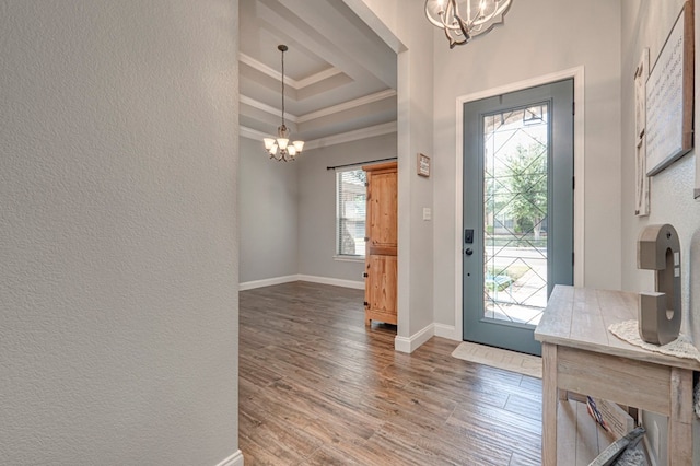 foyer with baseboards, ornamental molding, wood finished floors, and a notable chandelier