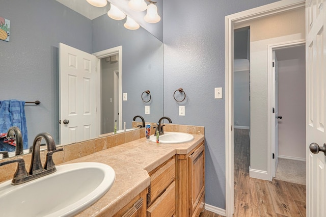 bathroom featuring a sink, baseboards, double vanity, and wood finished floors