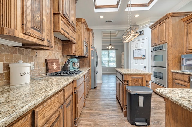 kitchen with crown molding, brown cabinetry, stainless steel appliances, a skylight, and visible vents