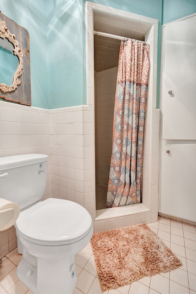 bathroom with tile walls, tile patterned flooring, a stall shower, and toilet