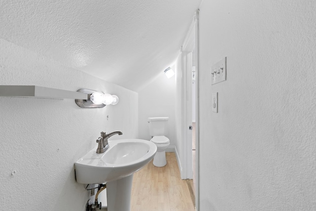 101 Waverly Dr, Midland, TX 79703 - bathroom with vaulted ceiling, wood finished floors, a textured wall, and a textured ceiling