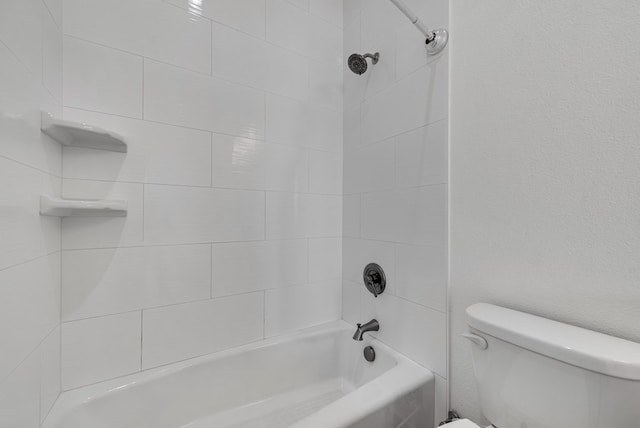 bathroom featuring toilet and tiled shower / bath