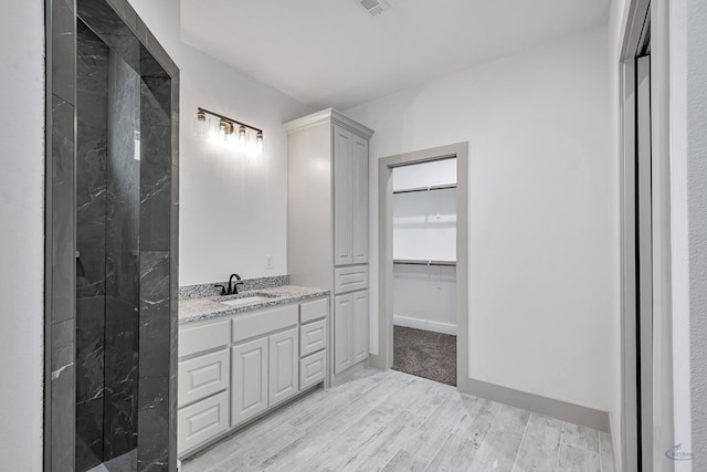603 S Benton, Midland, TX 79701 - bathroom with wood finished floors, vanity, a spacious closet, and a shower
