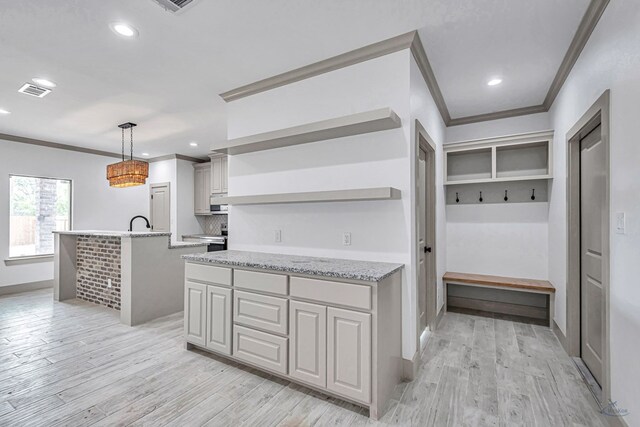 603 S Benton, Midland, TX 79701 - kitchen with open shelves, crown molding, light wood-type flooring, a center island with sink, and light stone countertops