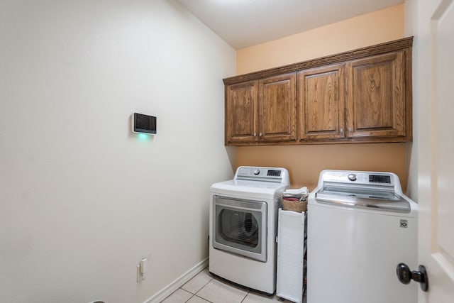 laundry room featuring cabinets, washing machine and dryer, and light tile patterned floors