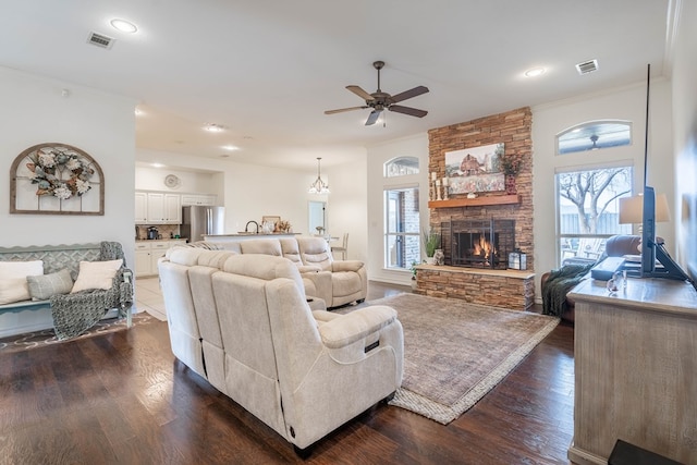 living room featuring crown molding, plenty of natural light, a stone fireplace, and dark hardwood / wood-style flooring