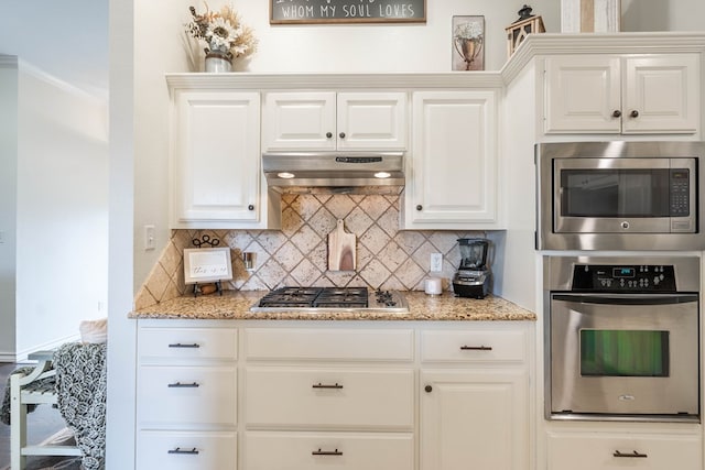 kitchen with light stone counters, ventilation hood, white cabinets, and appliances with stainless steel finishes