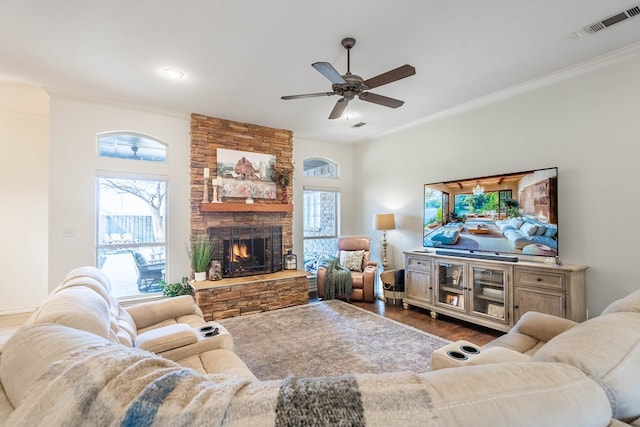 living room featuring dark hardwood / wood-style floors, a stone fireplace, crown molding, and a wealth of natural light