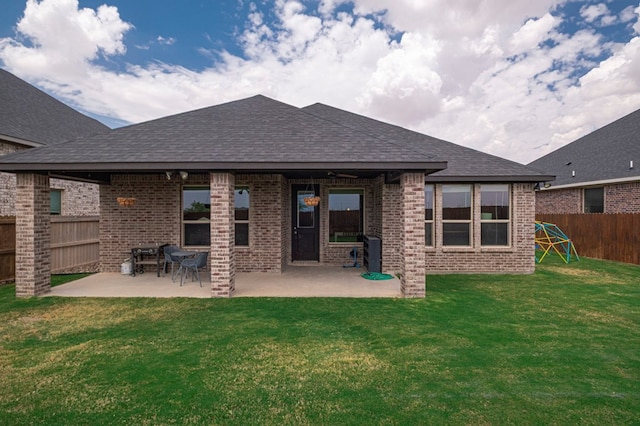rear view of house featuring a yard, brick siding, a fenced backyard, and a patio area