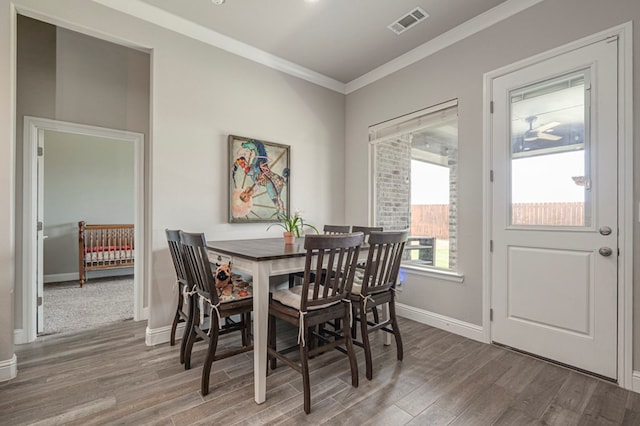dining room featuring visible vents, ornamental molding, baseboards, and wood finished floors