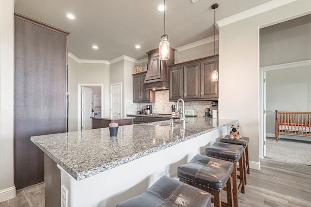 kitchen featuring baseboards, custom exhaust hood, and ornamental molding