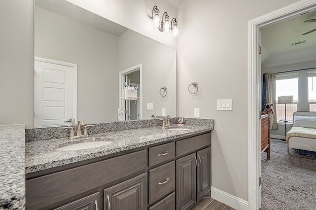 ensuite bathroom with double vanity, baseboards, visible vents, and a sink