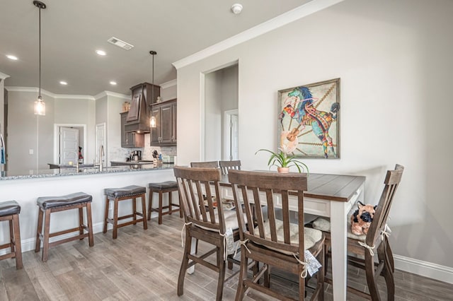 dining area with visible vents, crown molding, light wood-type flooring, baseboards, and recessed lighting