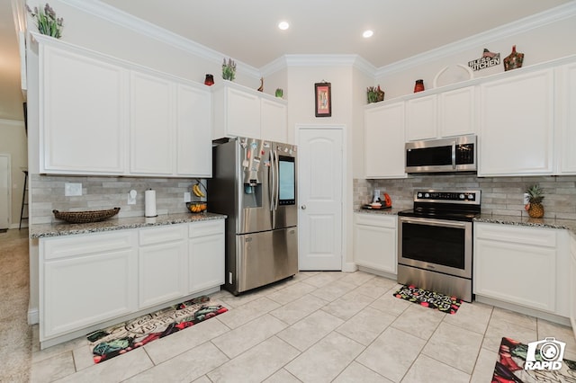 kitchen featuring light stone countertops, white cabinetry, stainless steel appliances, and crown molding