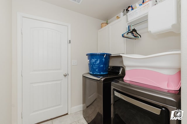 laundry area with light tile patterned floors, washer and clothes dryer, cabinet space, and baseboards