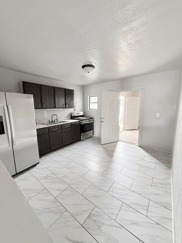 kitchen with sink, a textured ceiling, refrigerator with ice dispenser, dark brown cabinets, and gas stove