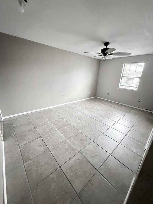 tiled spare room featuring ceiling fan