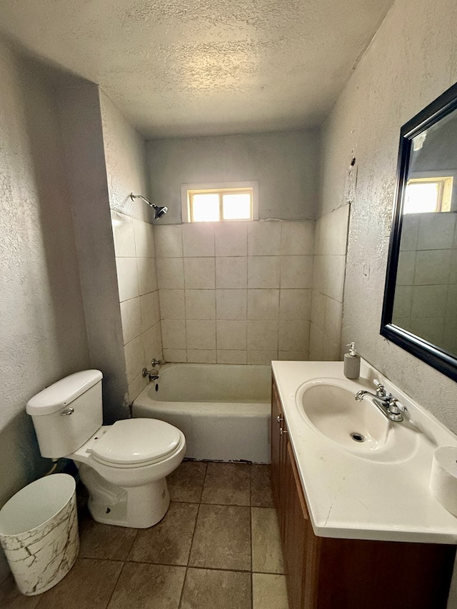 full bathroom with tile patterned flooring, toilet, vanity, tiled shower / bath, and a textured ceiling