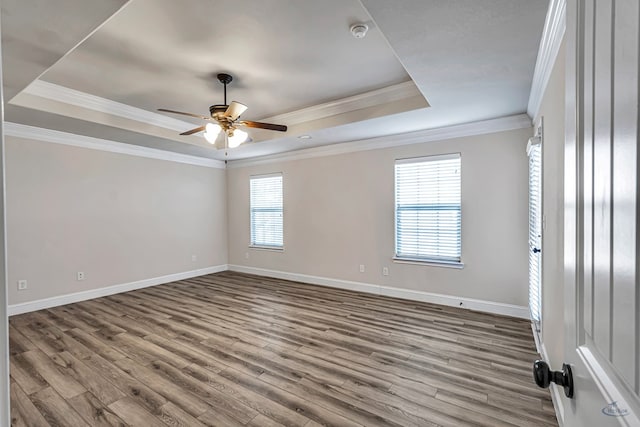 unfurnished room with hardwood / wood-style flooring, a wealth of natural light, a tray ceiling, and ornamental molding