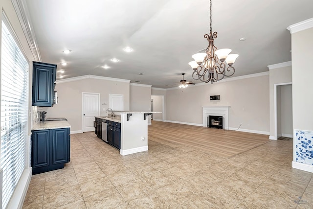 kitchen with sink, crown molding, hanging light fixtures, blue cabinets, and ceiling fan with notable chandelier