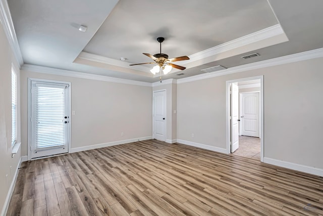 unfurnished room with ceiling fan, a tray ceiling, light hardwood / wood-style flooring, and ornamental molding