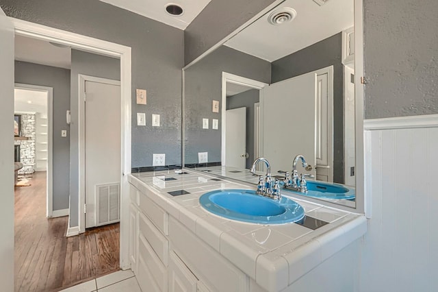710 W Nobles Ave, Midland, TX 79701 - bathroom featuring wood finished floors, a wainscoted wall, vanity, and a textured wall