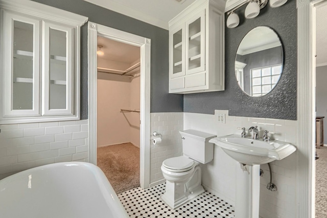 710 W Nobles Ave, Midland, TX 79701 - full bath featuring tile walls, a soaking tub, a spacious closet, toilet, and wainscoting