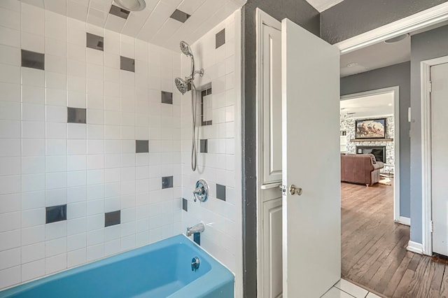 710 W Nobles Ave, Midland, TX 79701 - bathroom with bathtub / shower combination, a stone fireplace, wood finished floors, and baseboards